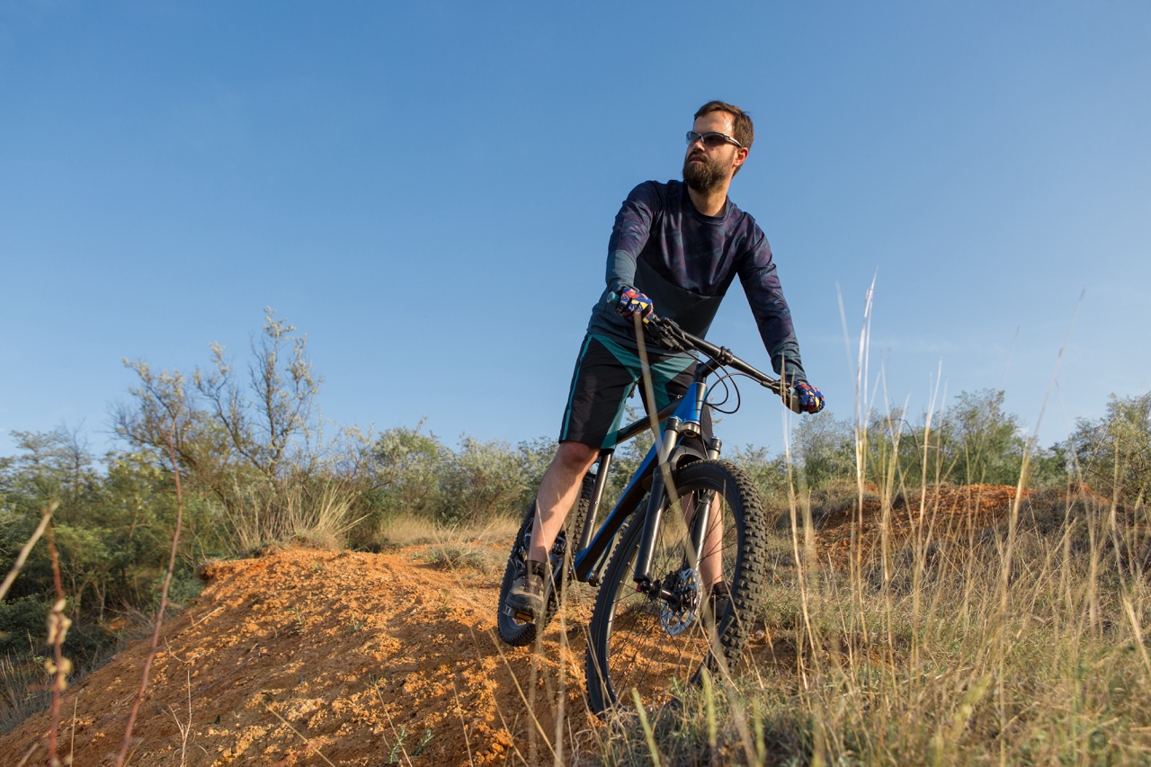 Conquering mountain peaks by cyclist in shorts and jersey on a modern carbon hardtail bike with an air suspension fork